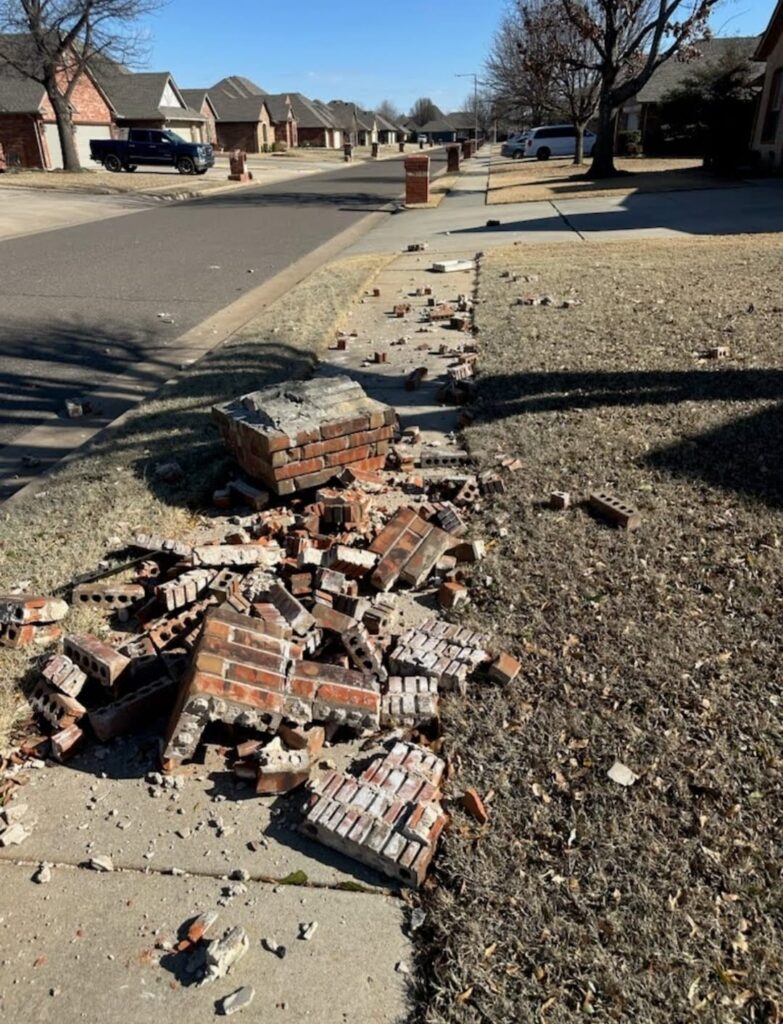 Damaged brick mailbox before rebuild with scattered bricks and debris